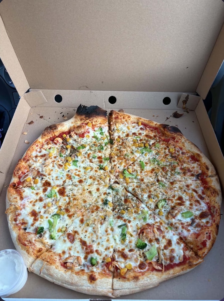 Duża pizza z różnymi dodatkami, pokrojona i gotowa do zabrania