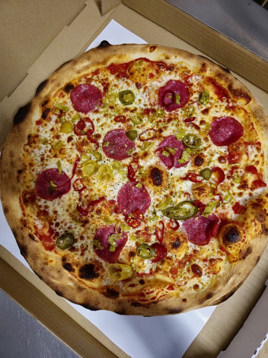 Pizza z pieca na cienkim cieście, z rumianymi brzegami i dodatkami